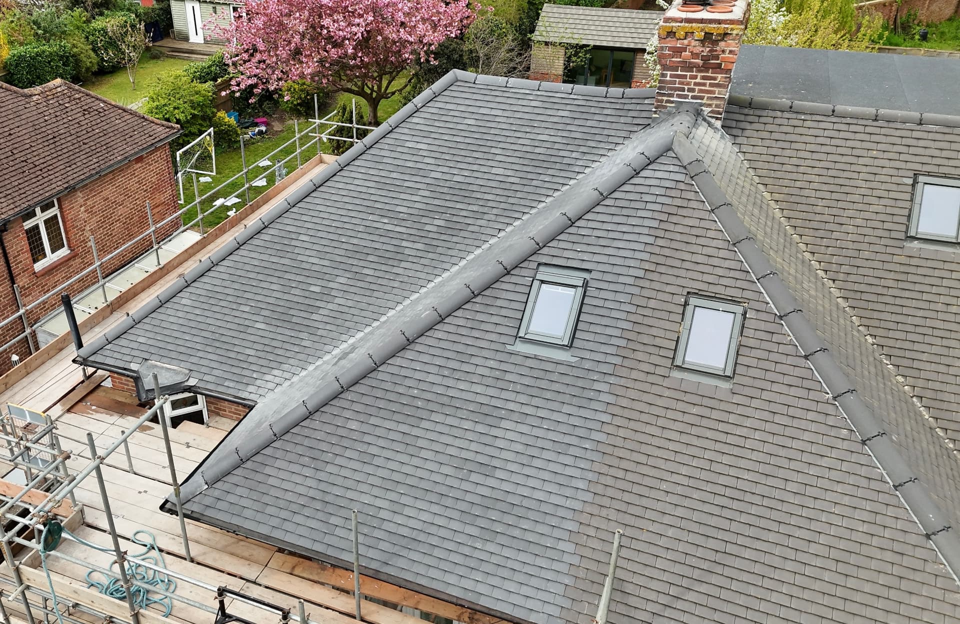 Newly laid grey slate pitched roof with lead ridge detail