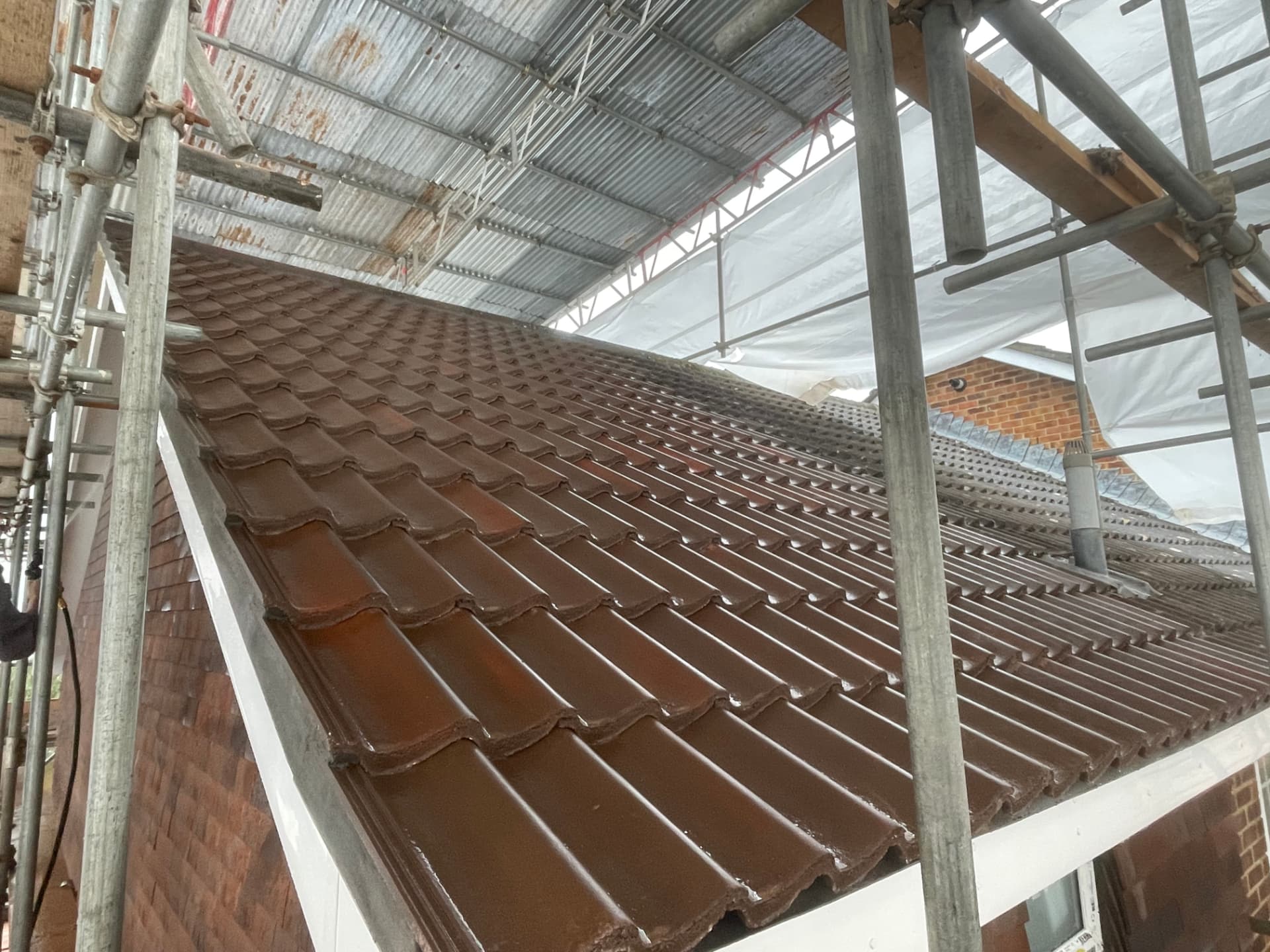 Fresh brown pantiles being laid under a temporary roof