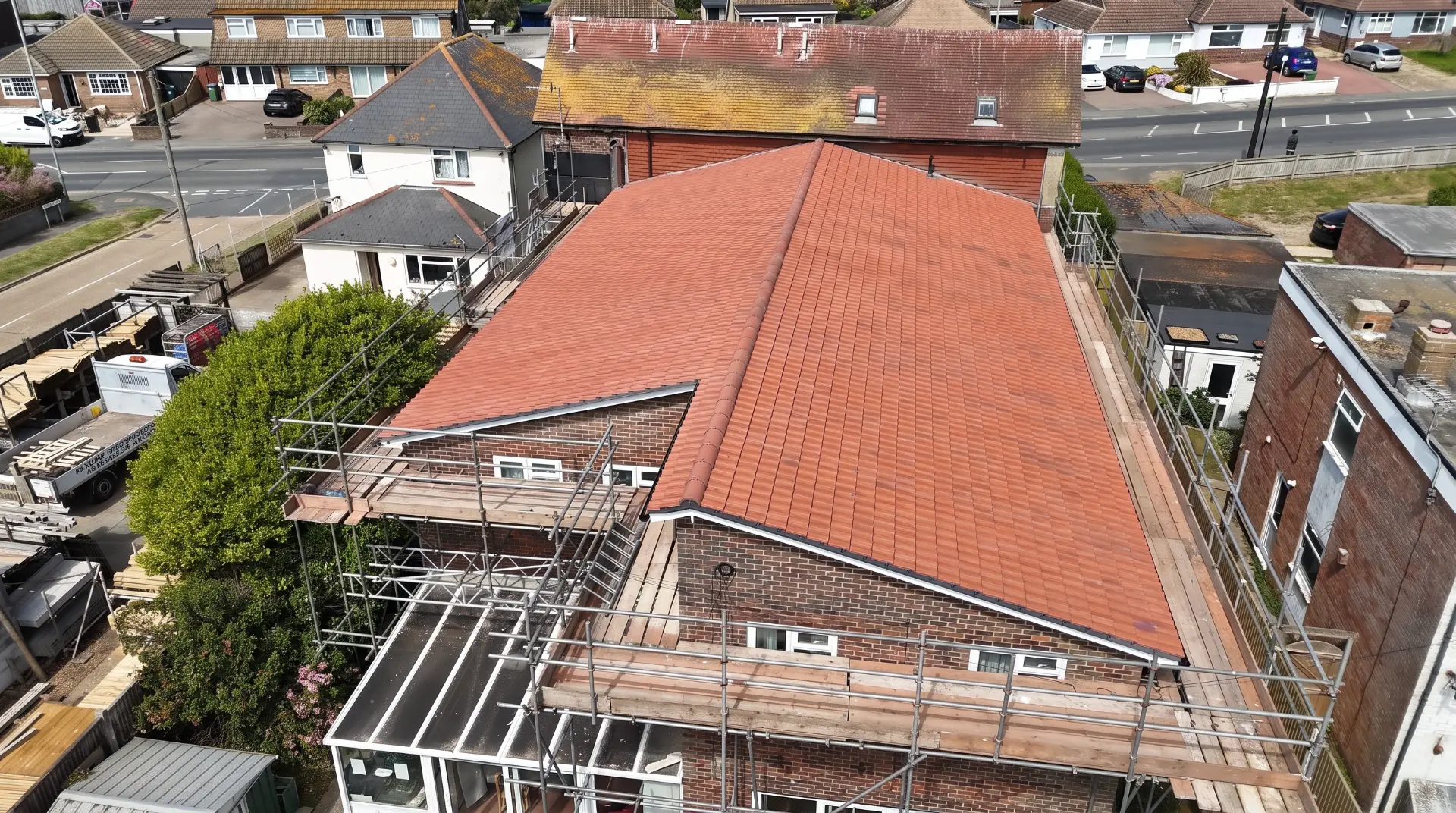 Completed terracotta clay tile pitched roof with scaffolding in place